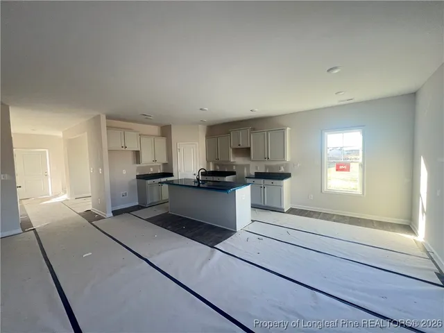 a view of kitchen and empty room with windows