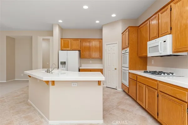 a view of a kitchen with kitchen island a counter top space a sink stainless steel appliances and cabinets