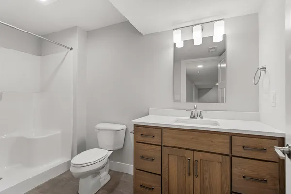 a bathroom with a toilet a sink a mirror and a shower