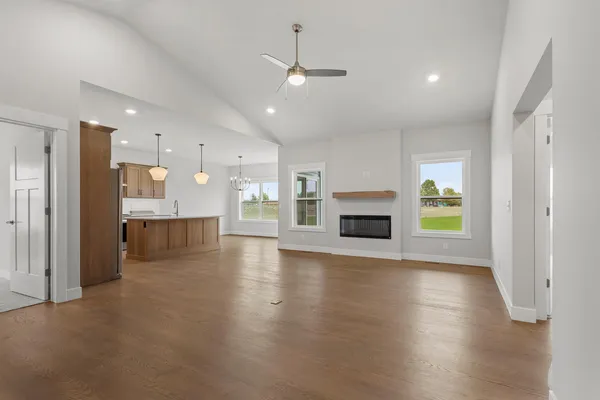 an empty room with wooden floor a fireplace and windows