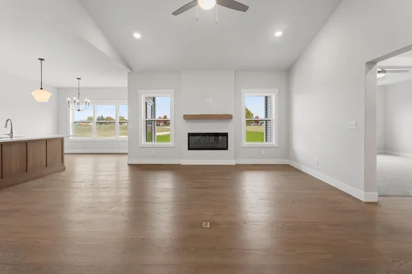 an empty room with wooden floor fireplace and windows