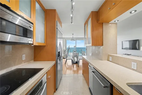a kitchen with a sink a counter top space and living room view