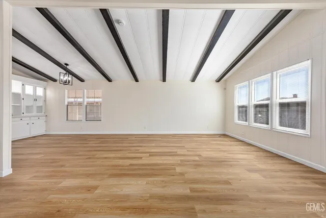 a view of an empty room with wooden floor and windows