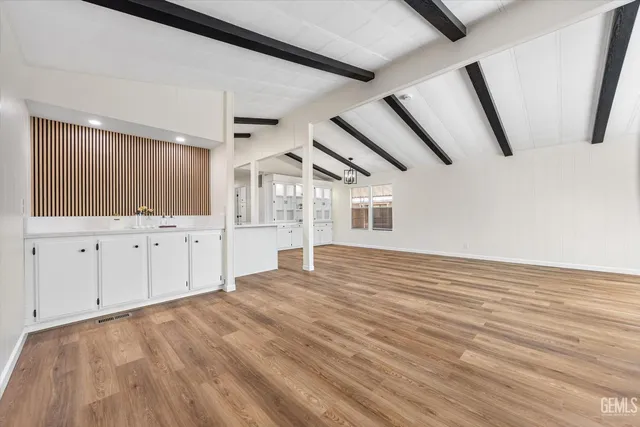 a view of an empty room with window and wooden floor