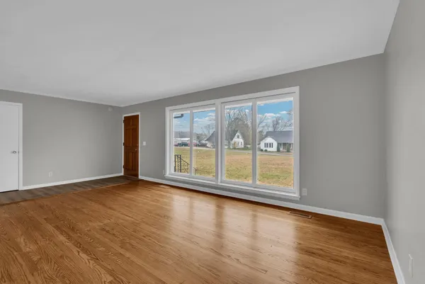 a view of an empty room with wooden floor and a window