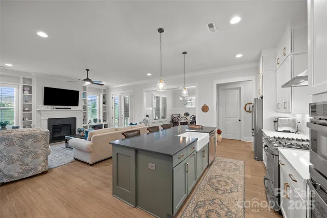 a kitchen with stainless steel appliances kitchen island granite countertop a table chairs stove and white cabinets