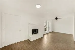 an empty room with wooden floor fireplace and windows