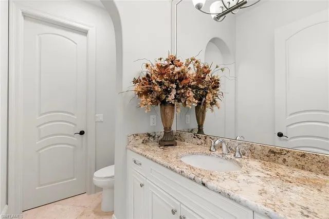 a bathroom with a granite countertop sink a toilet and a mirror