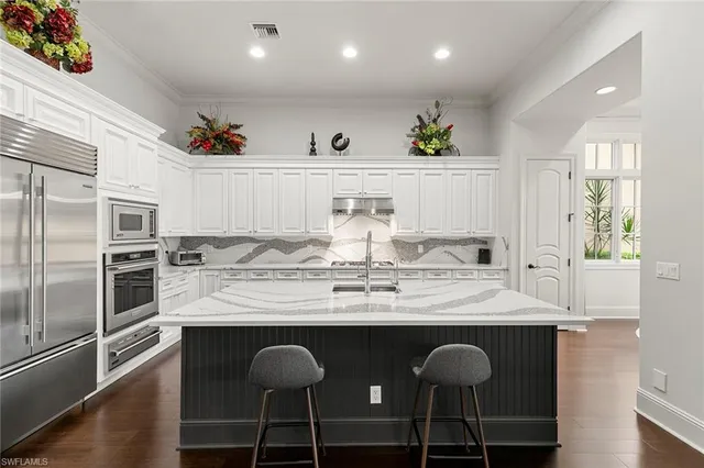 a kitchen with granite countertop a sink stainless steel appliances and white cabinets