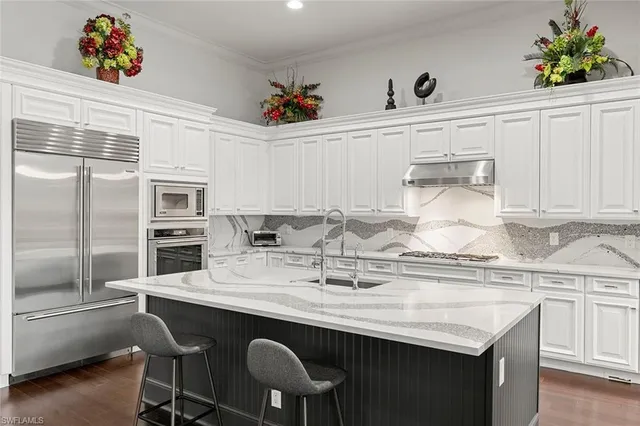 a kitchen with granite countertop a sink chairs and cabinets