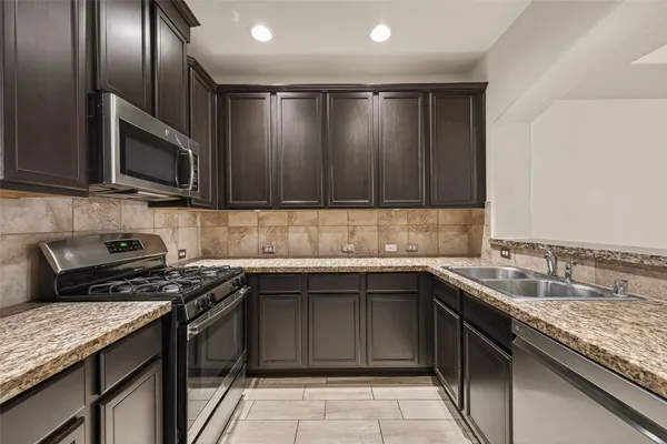 a kitchen with stainless steel appliances granite countertop a sink stove and microwave