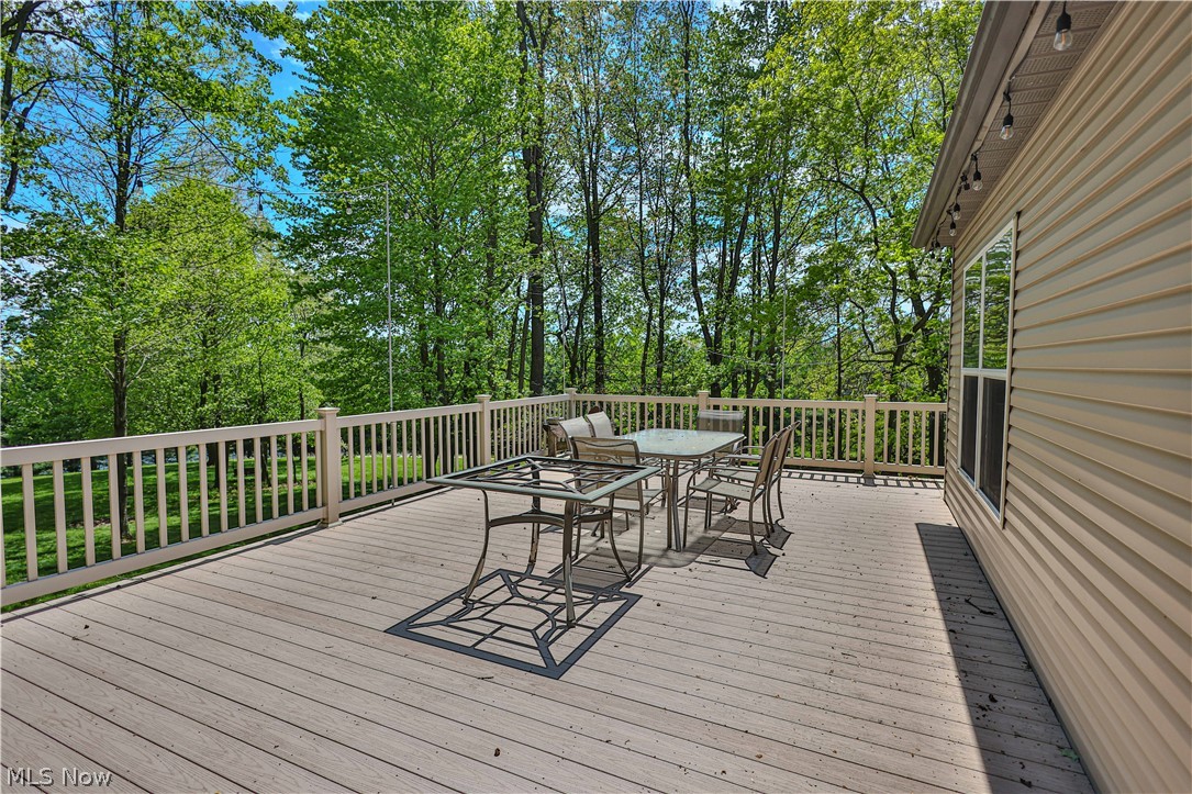 11154 Johnsford Road Southwest Beach City, OH 44608 - Photo 12 of 50 Spacious exterior deck with wood-finish decking and white railing, bordered by mature trees