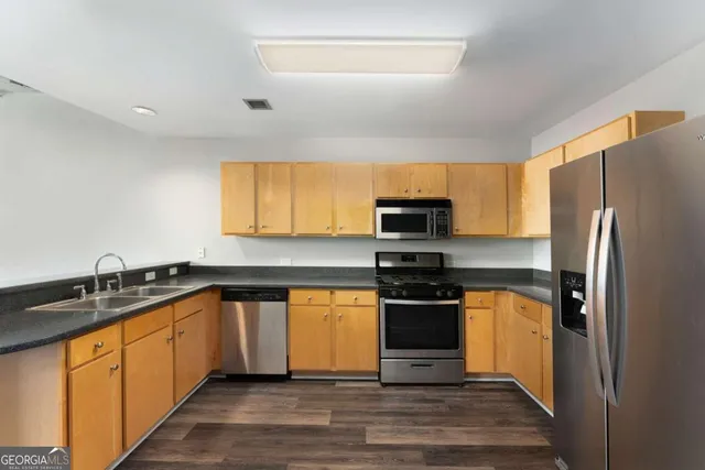 a kitchen with stainless steel appliances granite countertop a stove a sink and a refrigerator