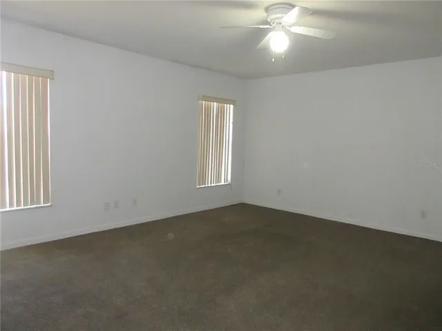 an empty room with a window and a ceiling fan
