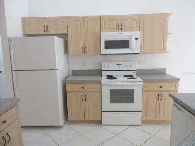 a white refrigerator freezer and a stove sitting inside of a kitchen