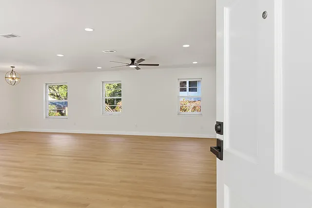an empty room with wooden floor cabinet and windows