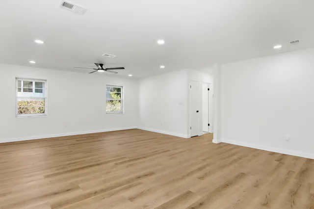 a view of empty room with wooden floor and windows
