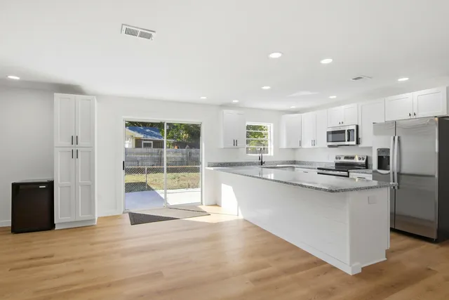 a large kitchen with stainless steel appliances granite countertop a large counter top and a wooden floors