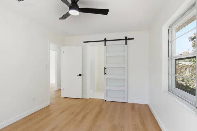 a view of an empty room with a window and wooden floor