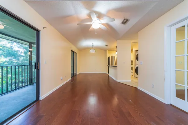 a view of an empty room with wooden floor and a window