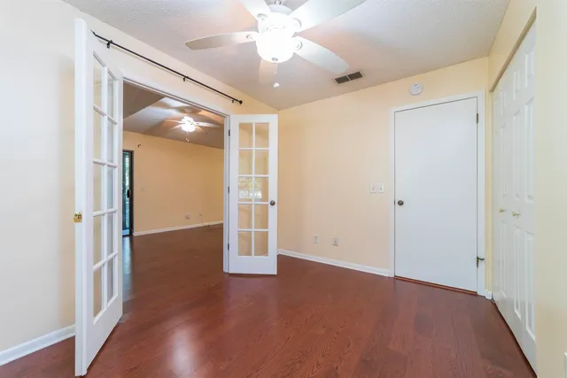 an empty room with wooden floor fan and windows