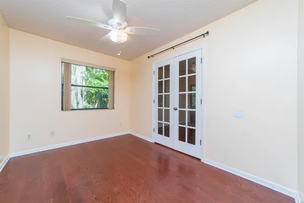 an empty room with windows and ceiling fan