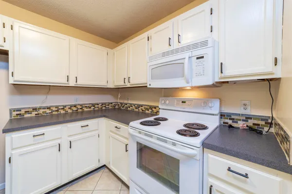 a kitchen with white cabinets and white appliances