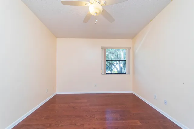an empty room with a chandelier fan and windows