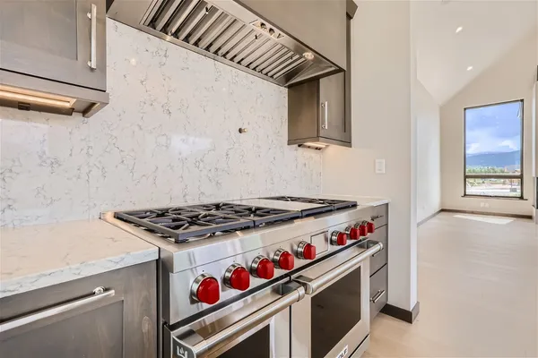a large kitchen with stainless steel appliances granite countertop a stove and a large window