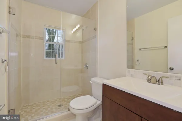 a bathroom with a sink a toilet a mirror and shower