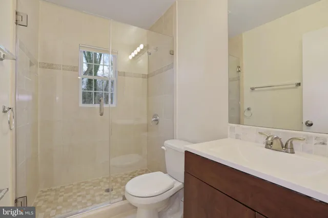 a bathroom with a sink a toilet a mirror and shower