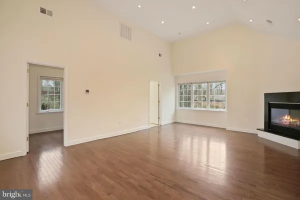 an empty room with wooden floor fireplace and windows