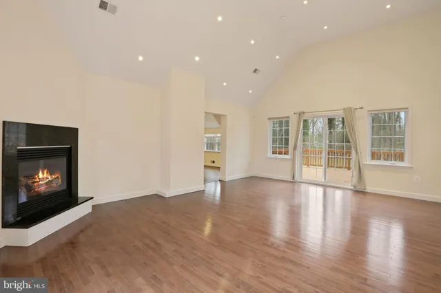 a view of an empty room with wooden floor fireplace and a window