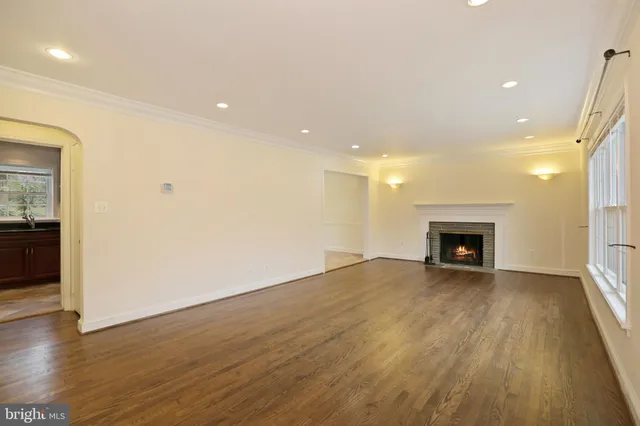 a view of an empty room with wooden floor fireplace and a window