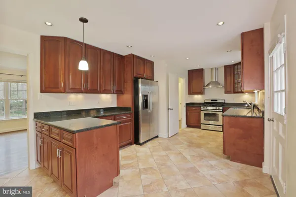 a kitchen with granite countertop a stove a sink a refrigerator and a counter top space