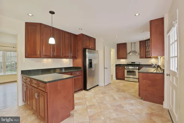 a kitchen with granite countertop a stove a sink a refrigerator and a counter top space