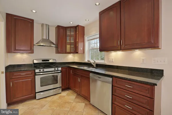 a kitchen with granite countertop wood cabinets stainless steel appliances and a sink