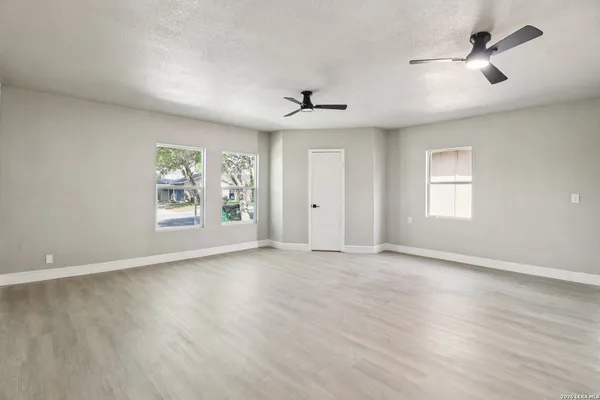 an empty room with windows and ceiling fan