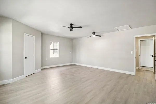 a view of an empty room with a window and wooden floor