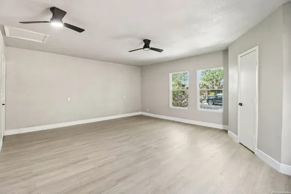 an empty room with wooden floor ceiling fan and windows