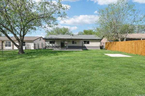 a view of a house with a big yard and large trees