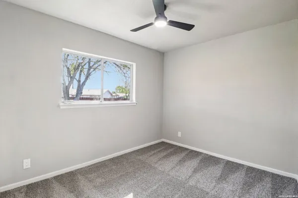 an empty room with a window and a ceiling fan