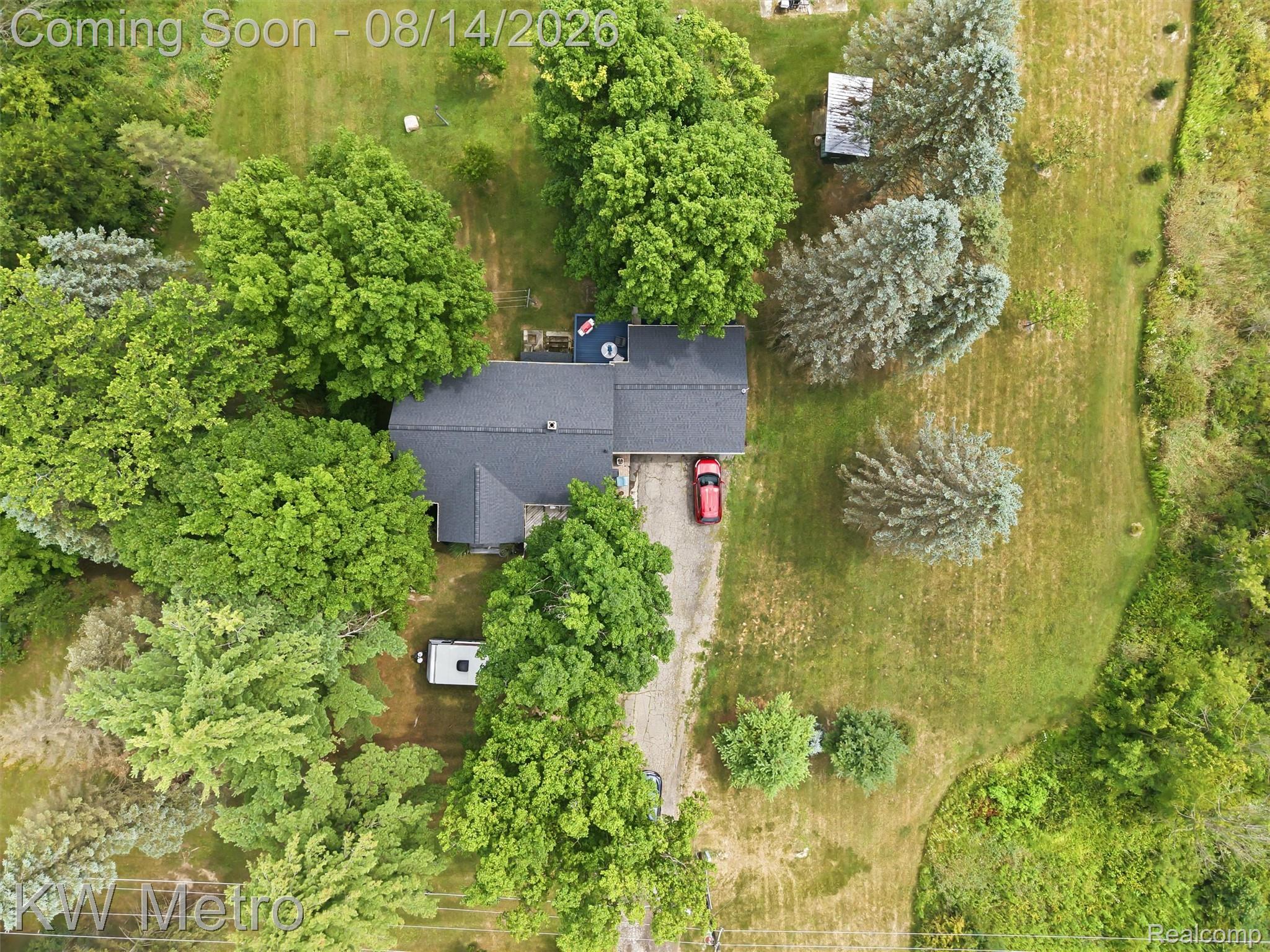 201 South Maple Leaf Road Lapeer, MI 48446 - Photo 59 of 70 Expansive property featuring a grey shingle roof, lush green foliage, mature trees, and a gravel driveway