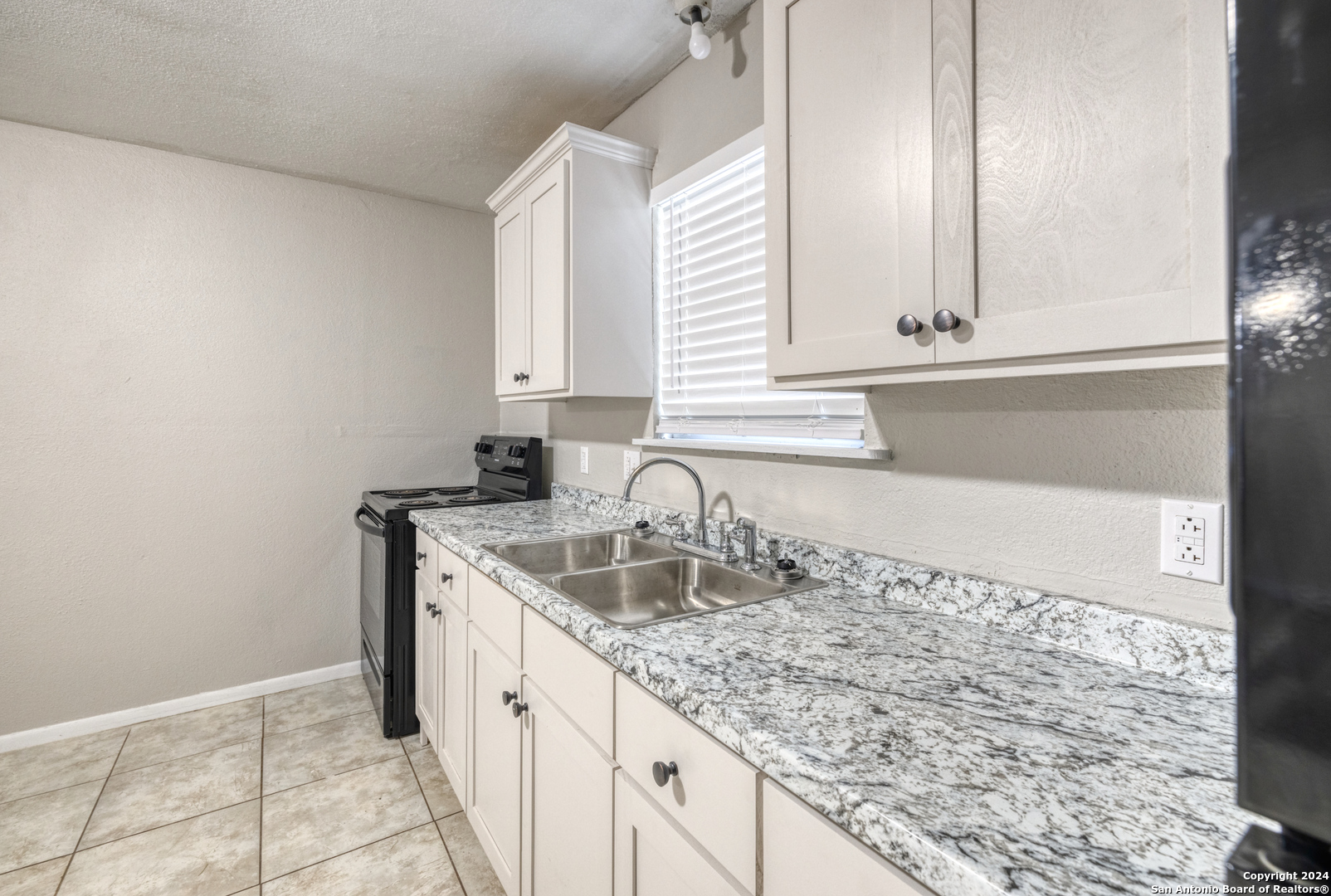 640 Roach Street Uvalde, TX 78801 - Photo 7 of 23 a kitchen with granite countertop a sink and a white cabinets
