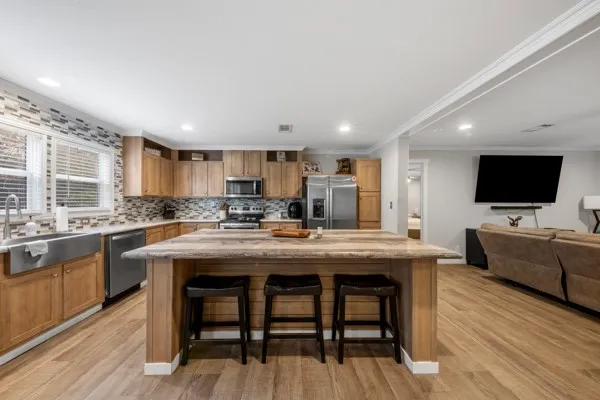 a kitchen with stainless steel appliances granite countertop a table chairs sink and cabinets