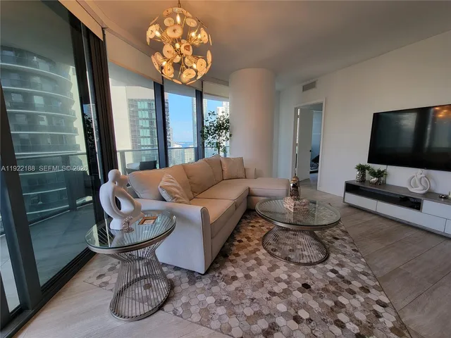 a living room with furniture a flat screen tv and a large window