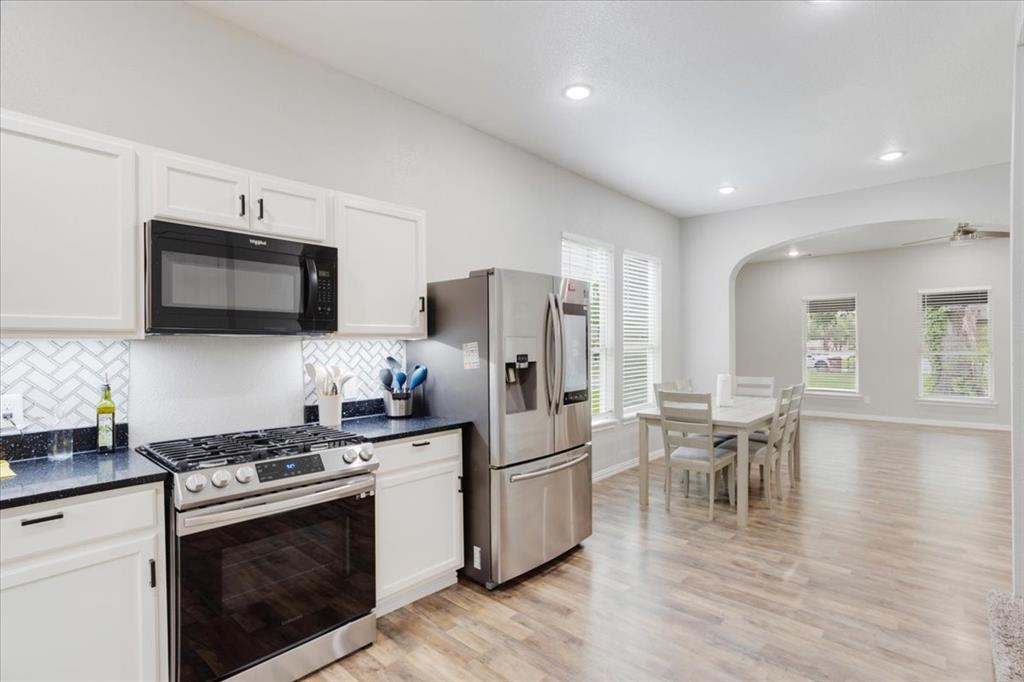 721 Maple Street Bonham, TX 75418 - Photo 11 of 30 a kitchen with stainless steel appliances a stove top oven a sink dishwasher a refrigerator white cabinets and wooden floor