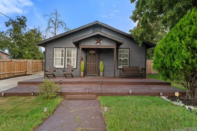 a view of a house with a small yard plants and large tree