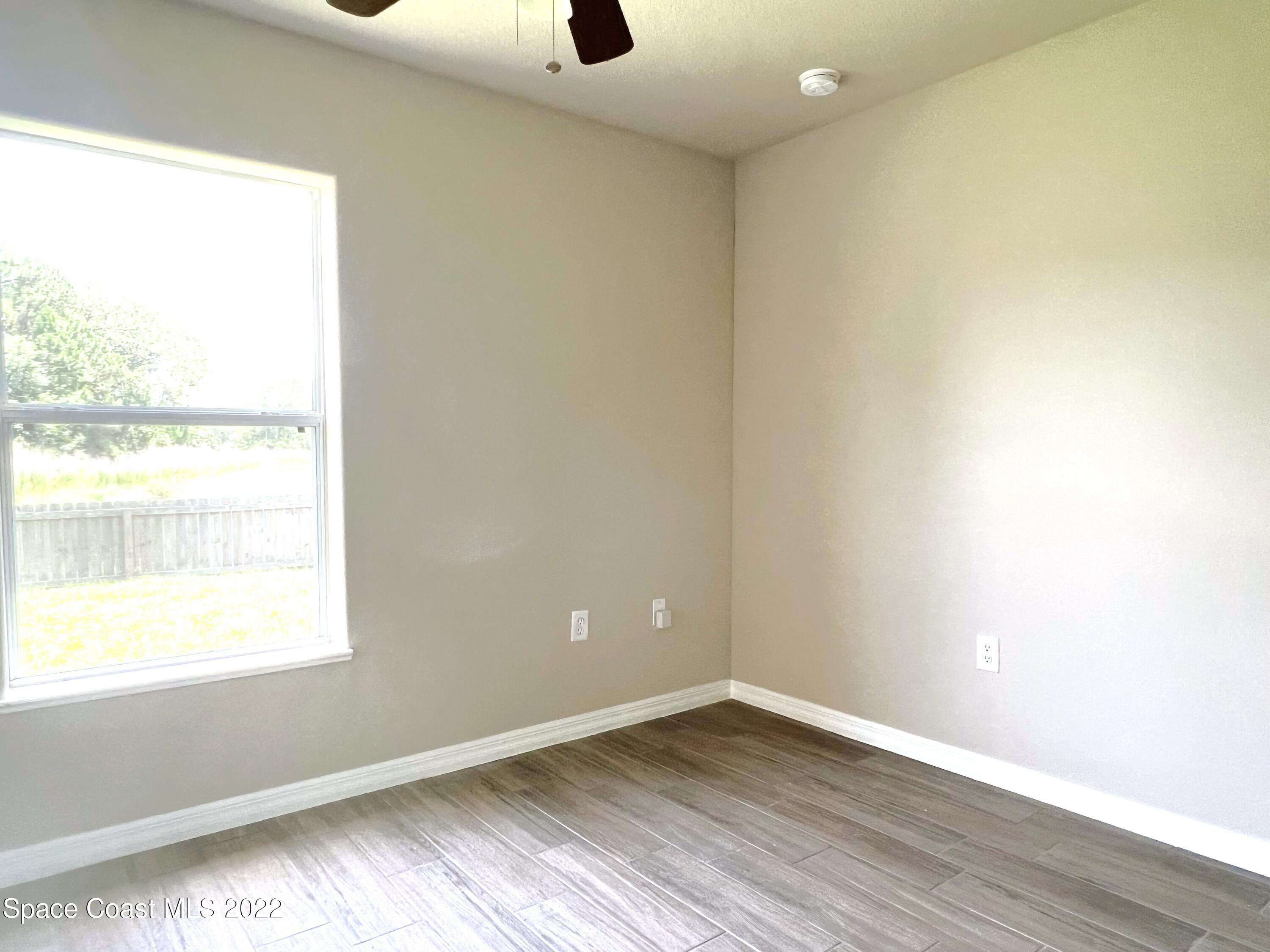 449 Alison Street Titusville, FL 32780 - Photo 15 of 18 an empty room with wooden floor and windows
