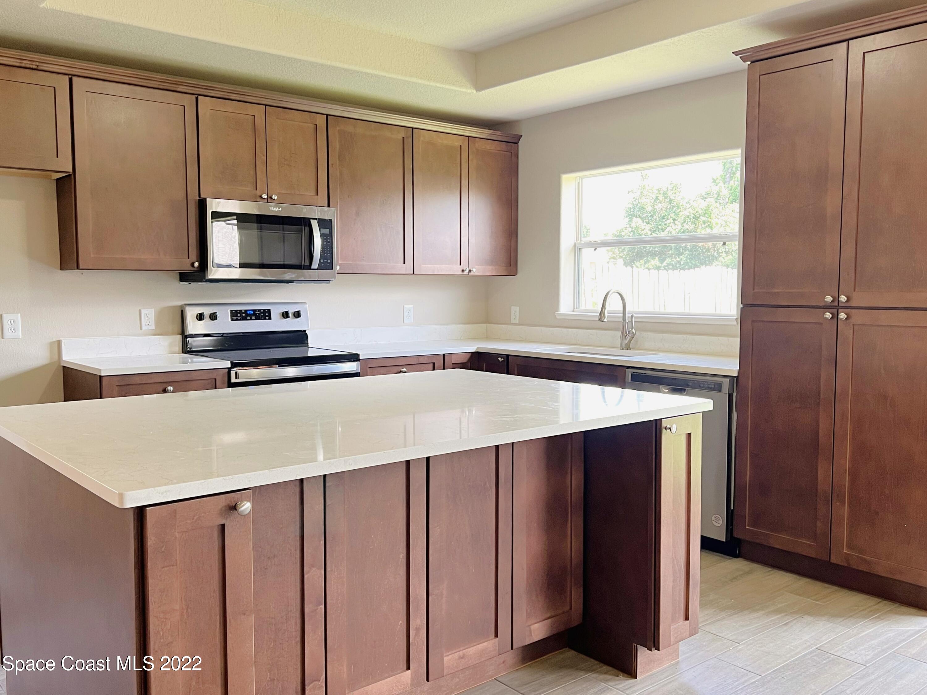 449 Alison Street Titusville, FL 32780 - Photo 8 of 18 a kitchen with stainless steel appliances a microwave sink refrigerator and cabinets